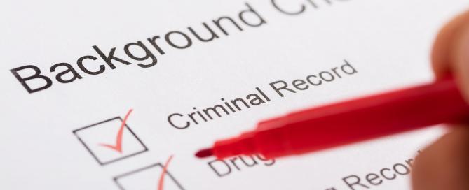 Someone uses a red pen to check boxes on a form titled Background Check.